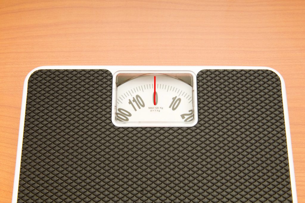 A scale with black rubber grips depicts a perfectly balanced weight of zero